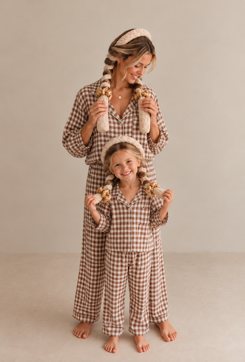 Mom and mini wearing matching oatmeal CurlBands with gold silk scrunchies in brown gingham pajamas