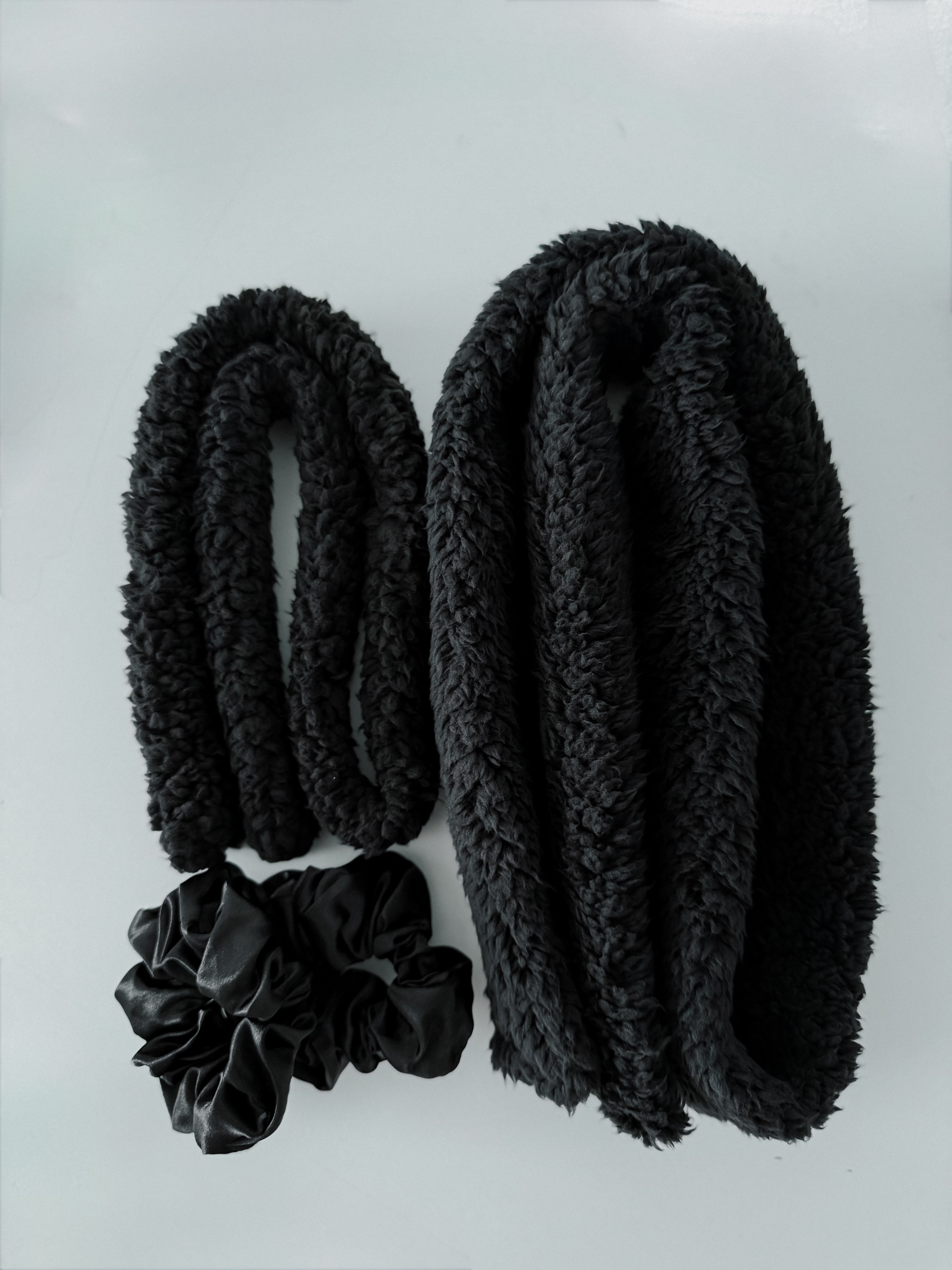 Rolled black fluffy CurlBands with black silk scrunchies from the Black Curl Kit for heatless curls