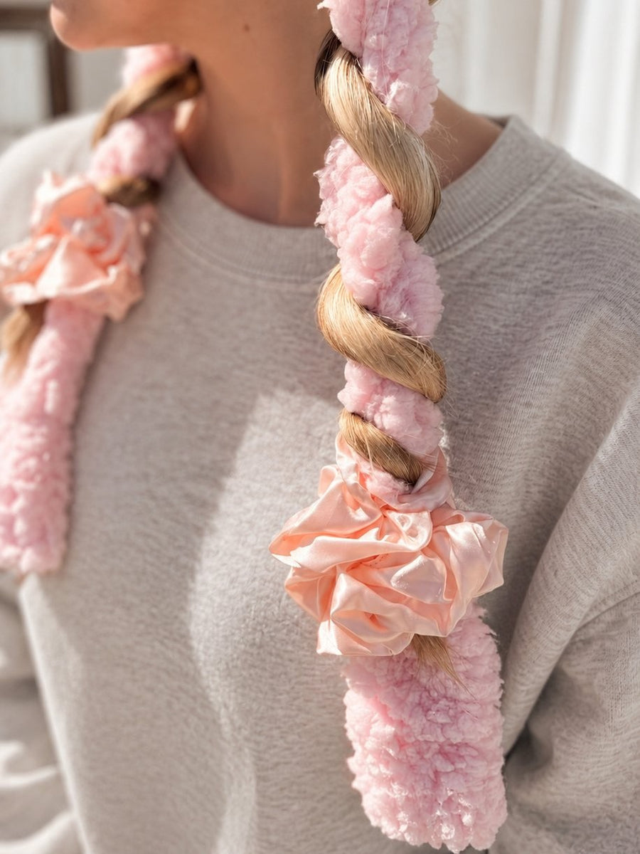 Blonde hair braided around a pink BeachWave CurlBand with peach scrunchies