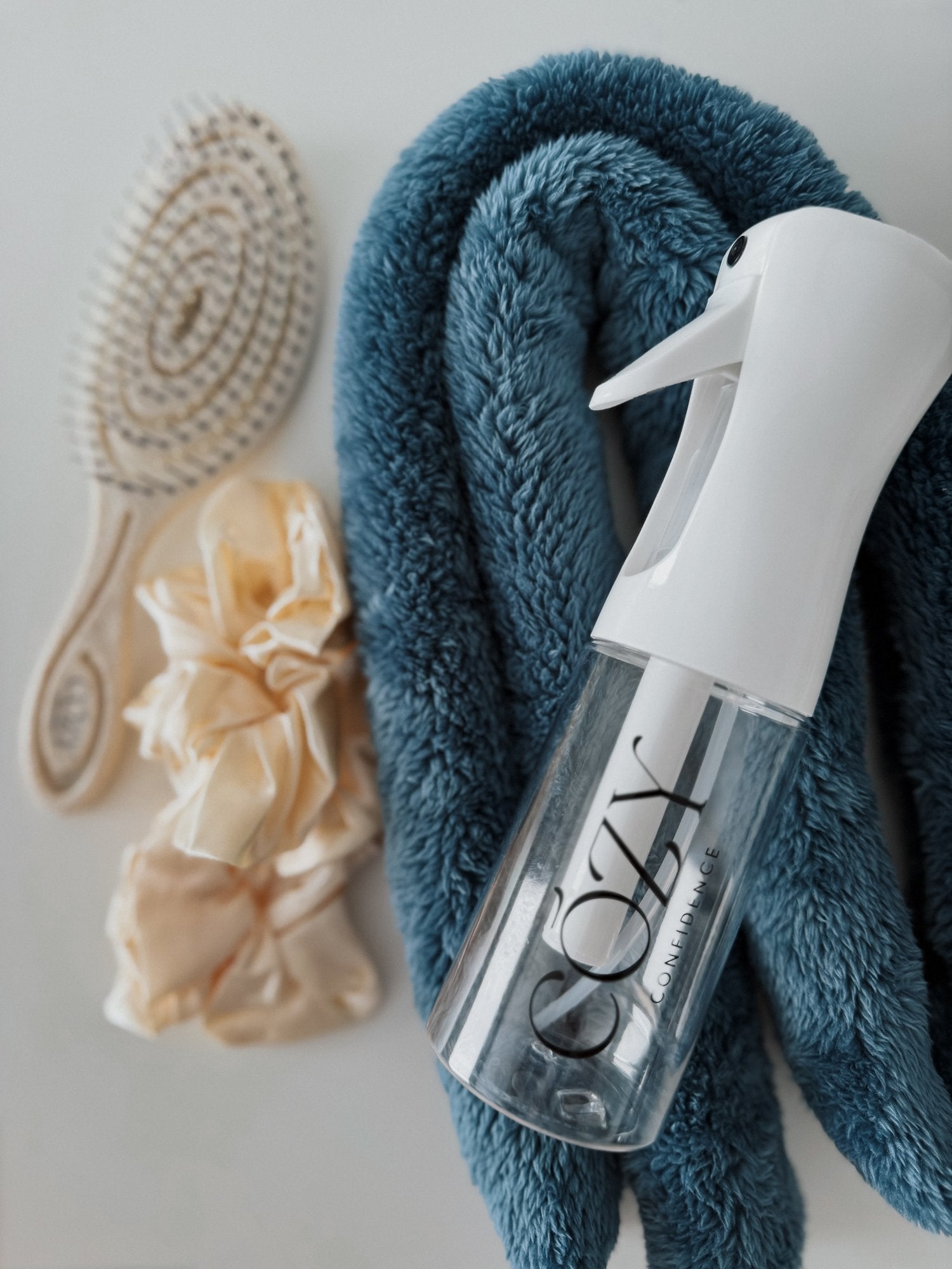 Capri Curl Kit for heatless curls with a teal blue fluffy CurlBand, buttercream silk scrunchies, beige Volume Brush and white Cozy Confidence spray bottle
