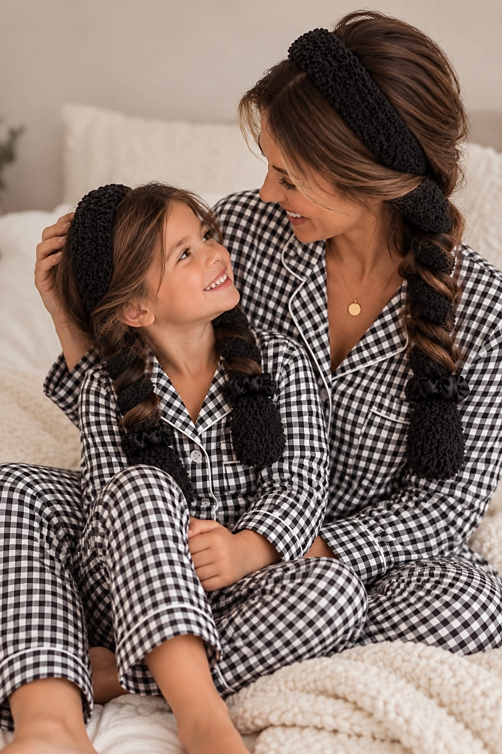 Mom and mini wearing matching black CurlBands with black silk scrunchies in black gingham pajamas
