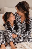Mom and mini wearing matching black CurlBands with black silk scrunchies in black gingham pajamas