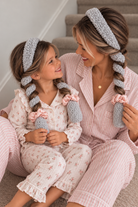 Mom and mini wearing matching light grey Cloud CurlBands with blush pink silk scrunchies in pink pajamas