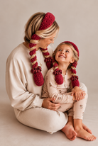 Mom and mini wearing matching raspberry CurlBands with deep burgundy silk scrunchies in cream pajamas