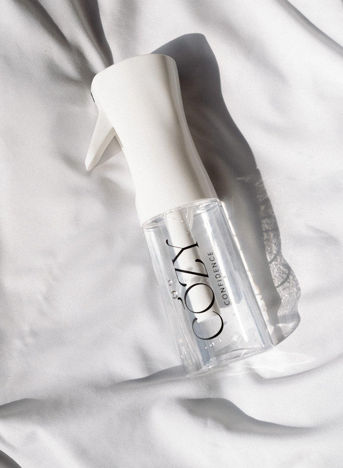 Fine mist spray bottle included in the Raspberry Curl Kit for heatless curls, on white sheets