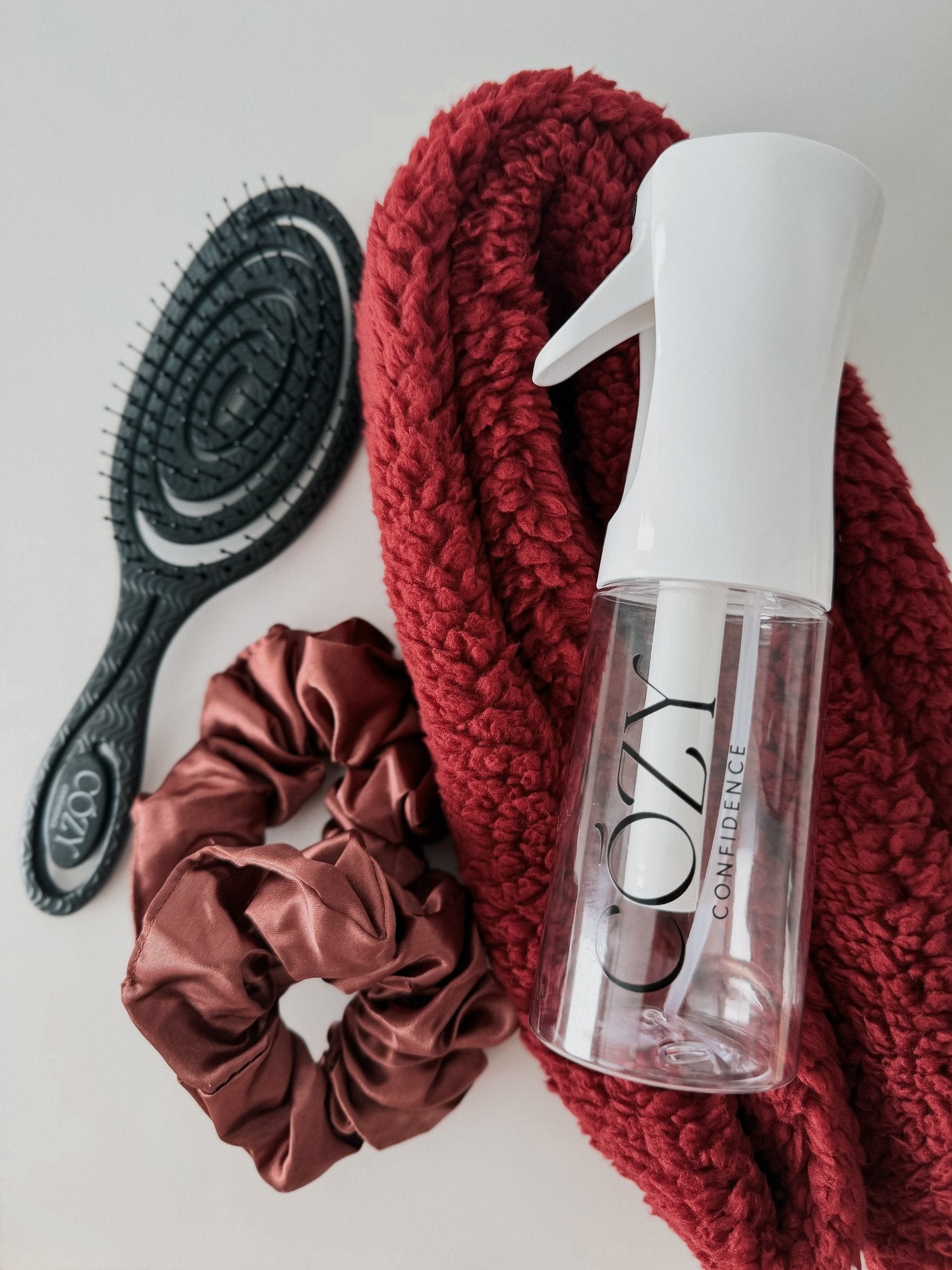 Raspberry Curl Kit for heatless curls with a deep red fluffy CurlBand, rust brown silk scrunchies, black Volume Brush and white Cozy Confidence spray bottle