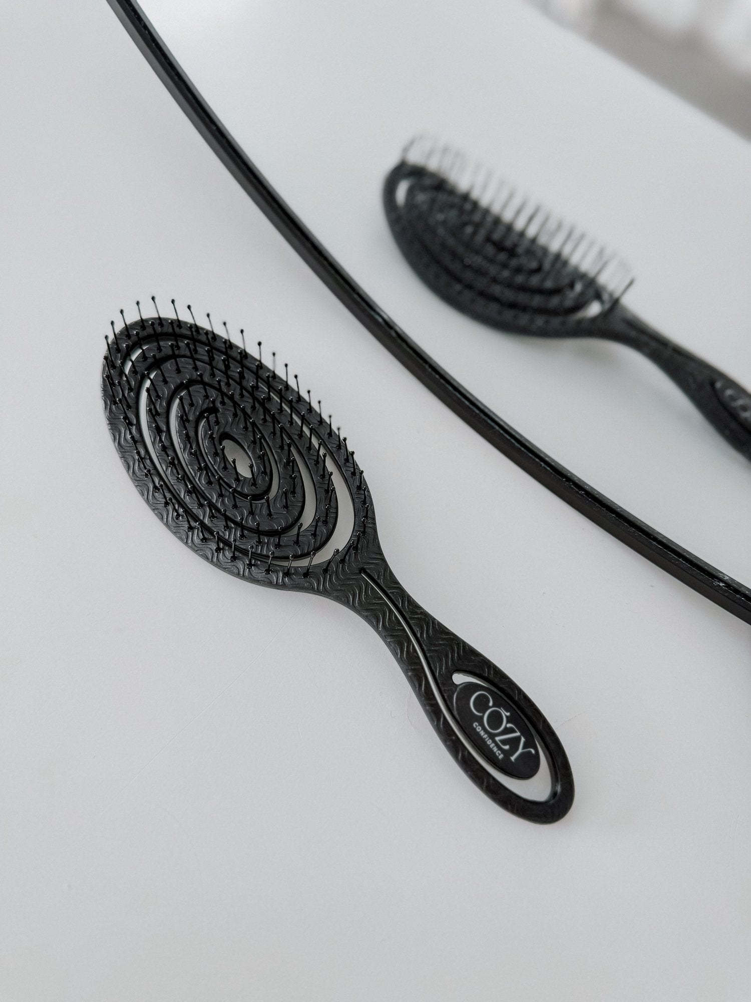 Black Volume Brush included in the Slate Curl Kit for heatless curls, shown beside a round mirror