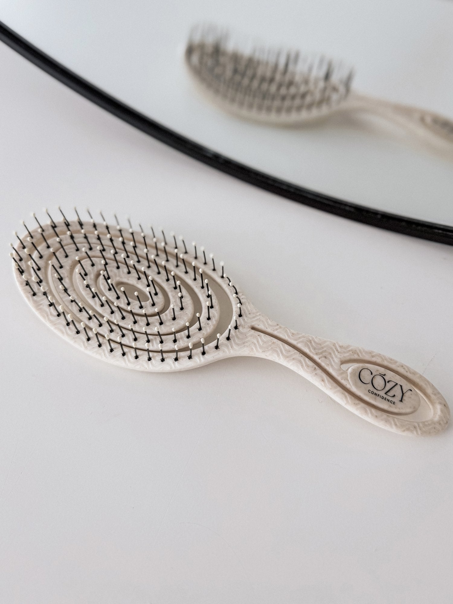 Oatmeal Volume Brush included in the Vanilla Curl Kit for heatless curls, shown beside a round mirror